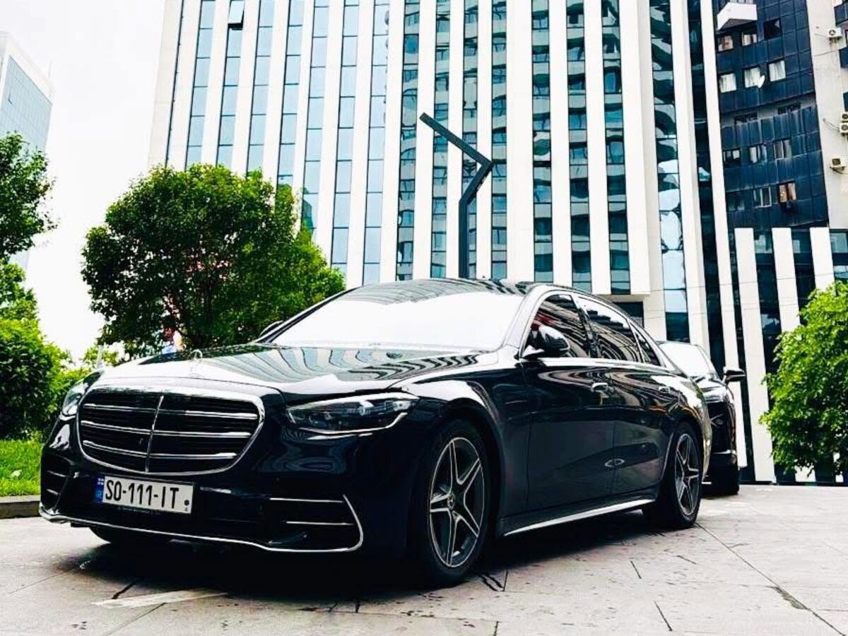 The SOIT Mercedes-Benz S-Class beside a glass tower in Tbilisi.
