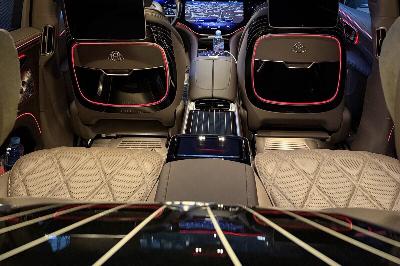 Two quilted rear seats in a Mercedes-Maybach EQS seen from behind, with screens on the front seatbacks beyond them.