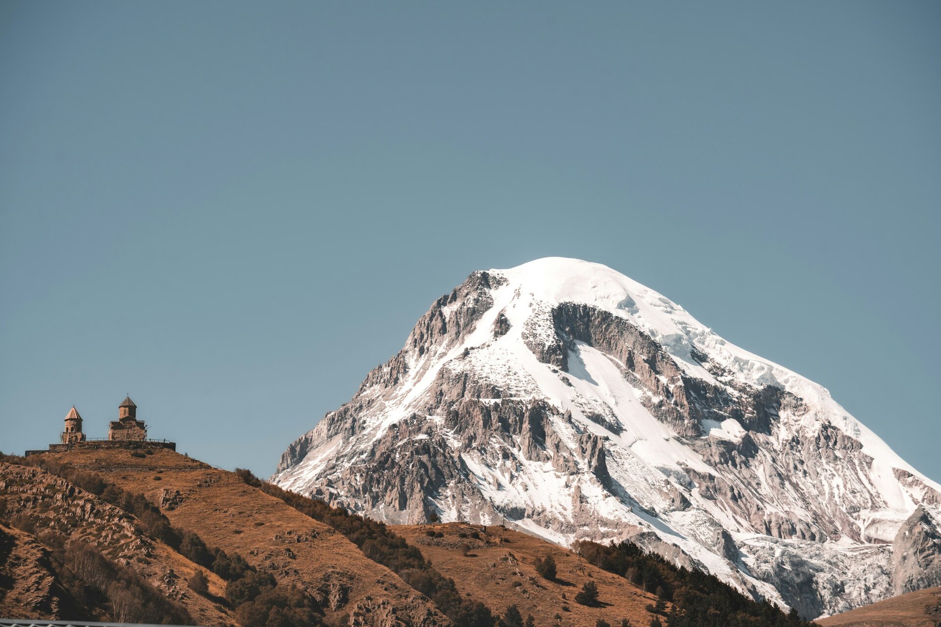 Gergeti Trinity Church on a ridge below the snow-capped slopes of Mount Kazbek.