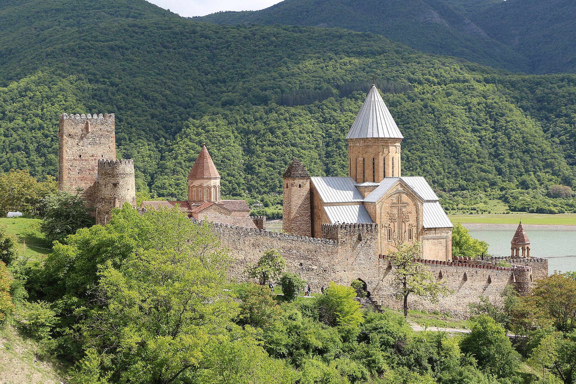 The 17th-century Ananuri fortress on the bank of the Jinvali reservoir along the Georgian Military Highway, its stone walls and conical church domes framed by wooded mountains.