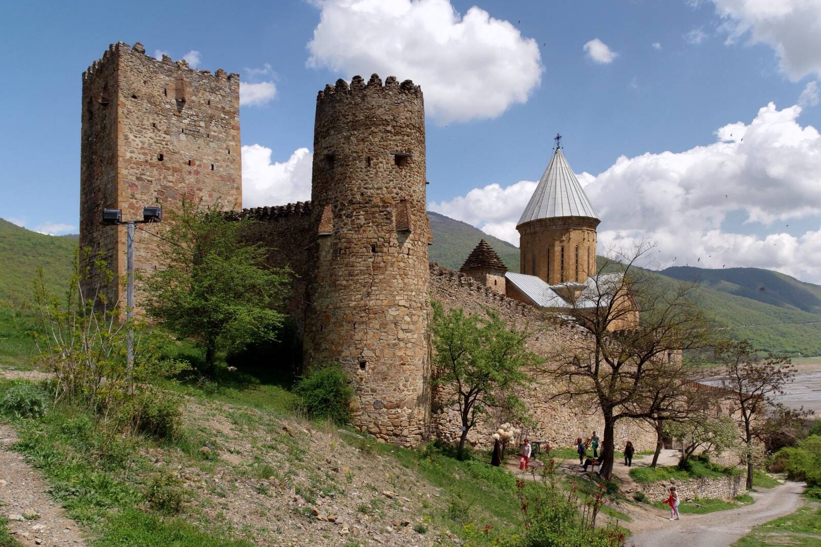 Ananuri castle above the Zhinvali reservoir on the Georgian Military Road, stone walls and a domed church against forested hills.