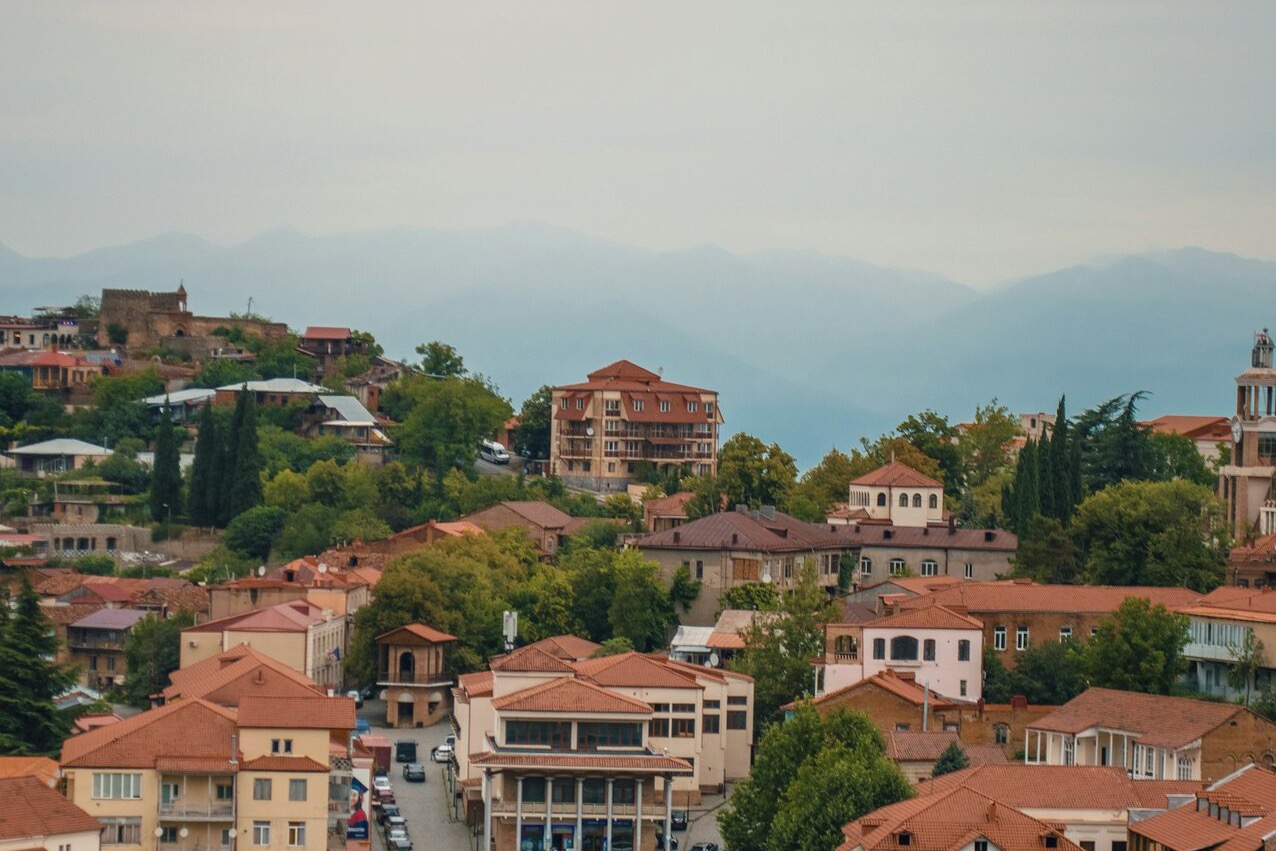 The red tile rooftops of Sighnaghi descending toward the Alazani valley, the Caucasus mountains hazy in the distance.