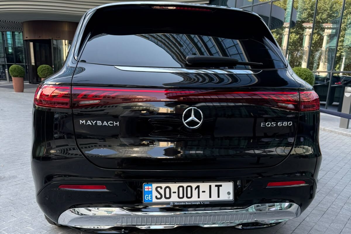The rear of a black Mercedes-Maybach EQS 680 with MAYBACH and EQS 680 badges, parked outside a building entrance in Tbilisi.