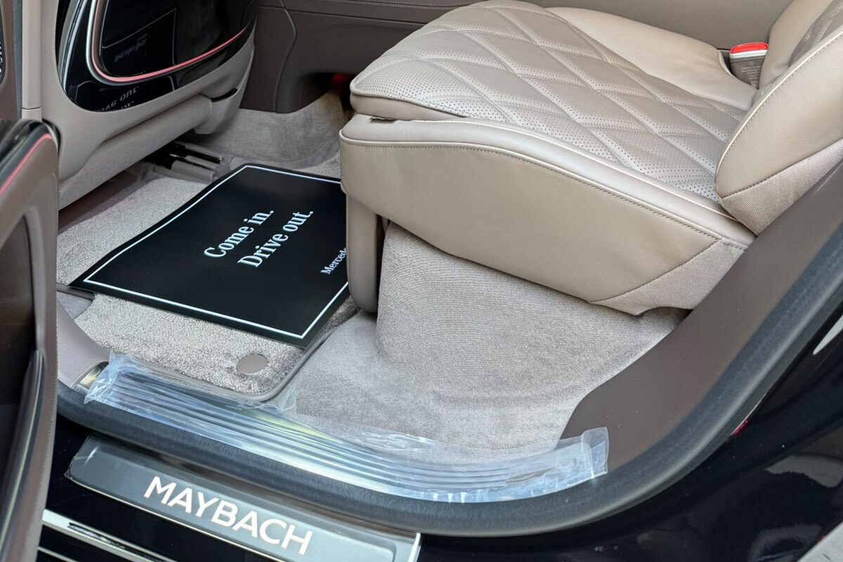 The rear footwell of a Mercedes-Maybach EQS: the base of a quilted seat, a floor mat and the MAYBACH sill plate.