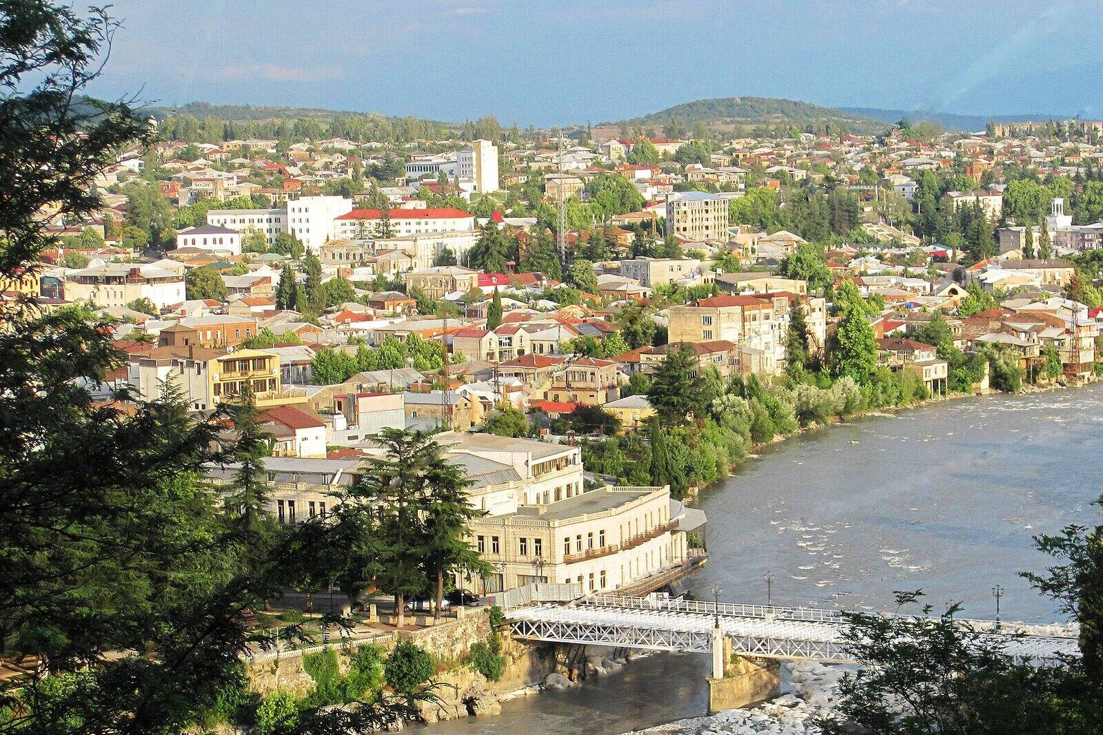 Central Kutaisi seen from Mount Gora, the White Bridge crossing the Rioni below rooftops spreading towards green hills.