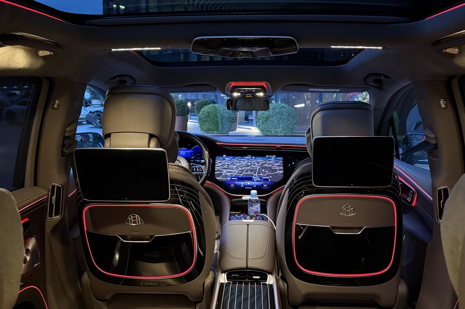 The rear cabin of a Mercedes-Maybach EQS looking forward: screens on the backs of the front seats, the centre console and the dashboard display.